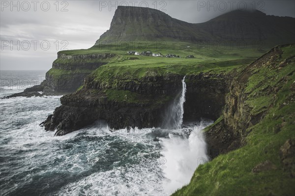 Denmark, Faroe Islands, Gasadalur village, Mulafossur Waterfall, Mulafossur Waterfall falling from cliff into ocean
