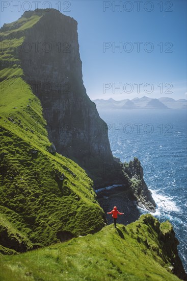 Denmark, Faroe Islands, Klaksvik, Trollanes, Woman standing on cliff and looking at ocean