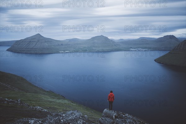 Denmark, Faroe Islands, Klaksvik, Woman standing on rock and looking at fjord