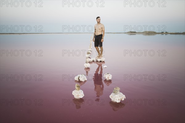 Ukraine, Crimea, Man standing on salt crystal in salt lake