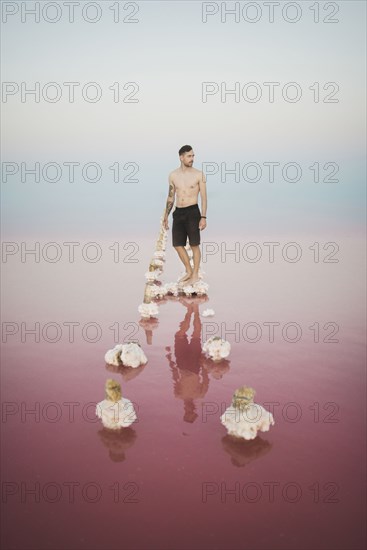 Ukraine, Crimea, Man standing on salt crystal in salt lake
