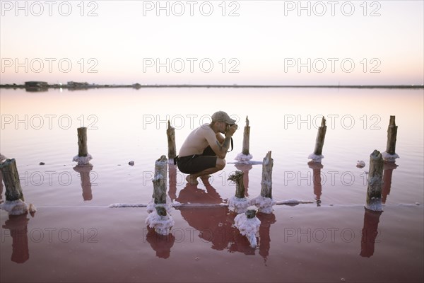 Ukraine, Crimea, Man standing in salt lake and taking photos