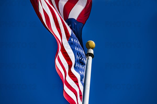 American flag blowing in wind against blue sky