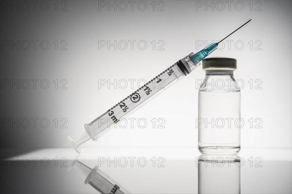 Studio shot of laboratory vial with liquid and syringe