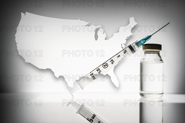 Studio shot of laboratory vial and syringe with USA shape in background