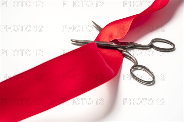 Studio shot of old fashioned scissors cutting red ribbon