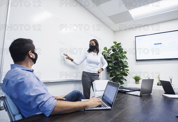 Businesswoman in face mask giving presentation in office