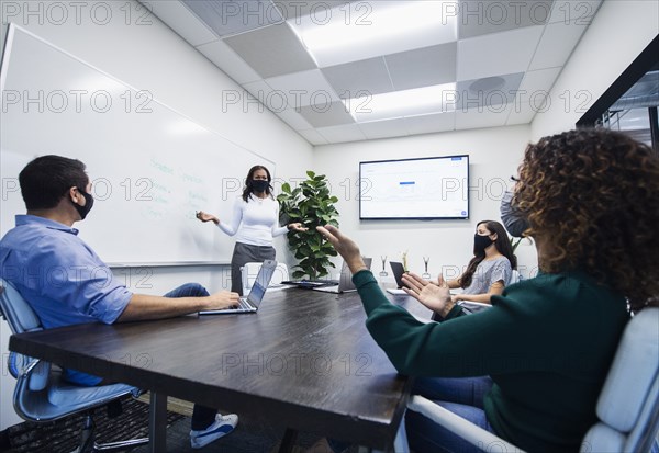 Businesswoman in face mask giving presentation in office