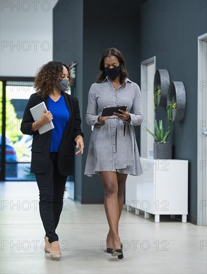 Businesswomen in face masks walking in office