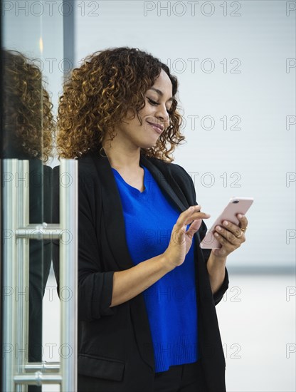 Smiling businesswoman using smart phone in office