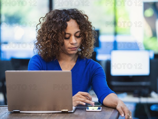 Woman text messaging at desk in office