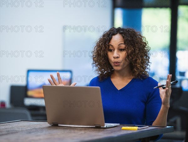 Woman looking at laptop at desk in office