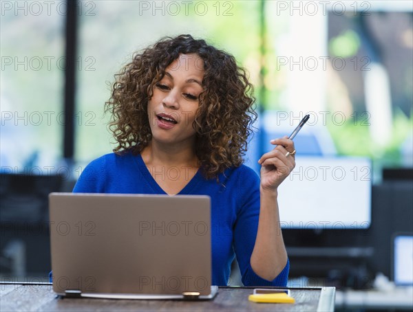 Woman using laptop at desk in office