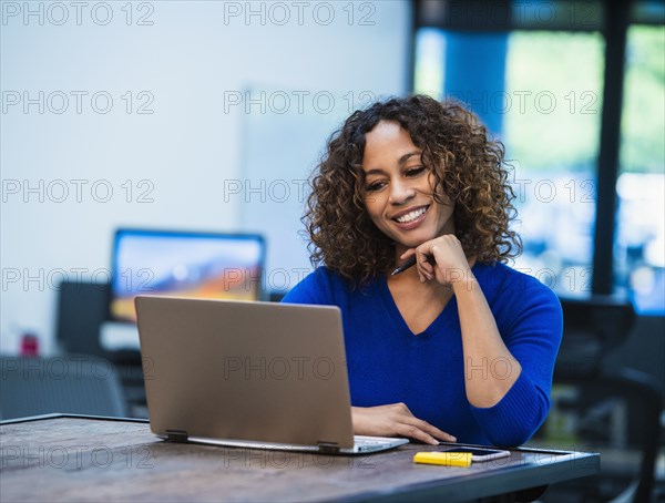 Smiling woman looking at laptop at desk in office