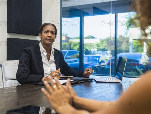 Two businesswomen talking at conference table