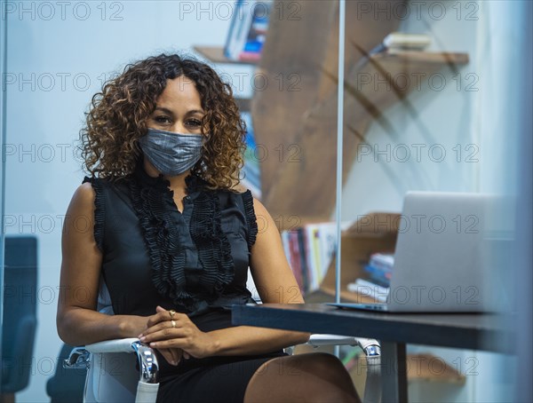 Portrait of businesswoman wearing face mask sitting at desk in office