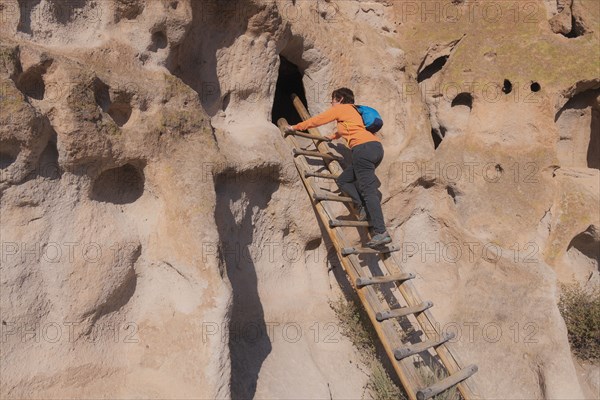 Woman climbing ladder to cliff dwellings in Bandelier National Monument