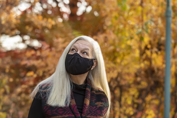 Portrait of senior woman wearing Covid protective mask outdoors in fall