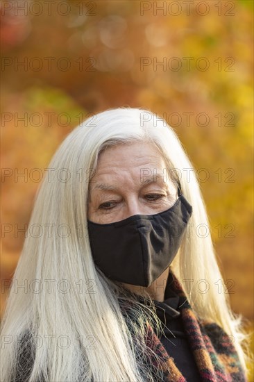 Portrait of senior woman wearing Covid protective mask outdoors in fall