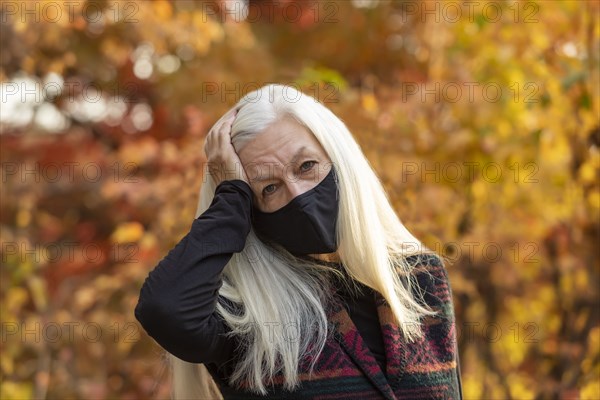 Portrait of senior woman wearing Covid protective mask outdoors in fall