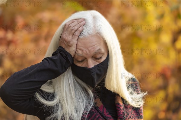 Portrait of senior woman wearing Covid protective mask outdoors in fall