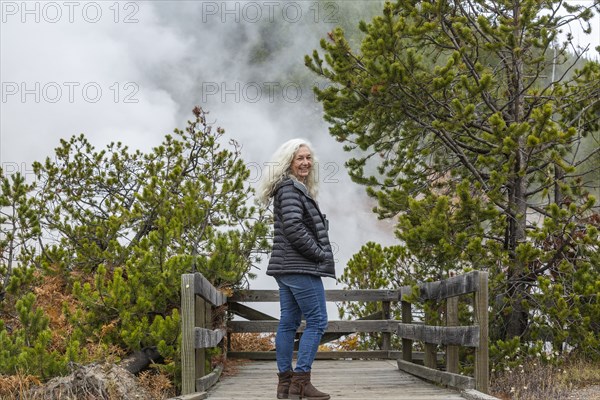 Senior female tourist standing on wooden observation point in Yellowstone National Park