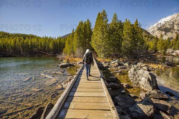 Senior woman walking on wooden path over Taggart Lake in Grand Teton National Park