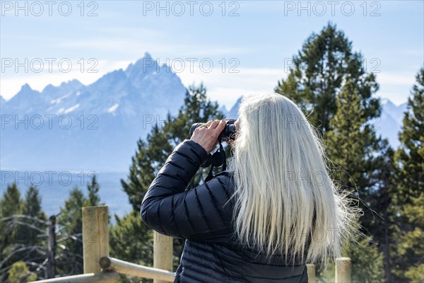 Senior woman looking through binoculars at landscape in Yellowstone National Park