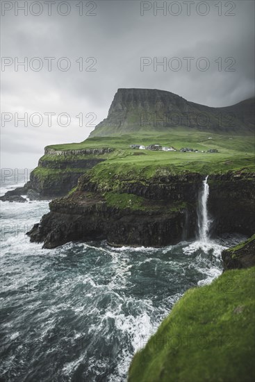 Coastline with Mulafossur Waterfall falling into Atlantic Ocean