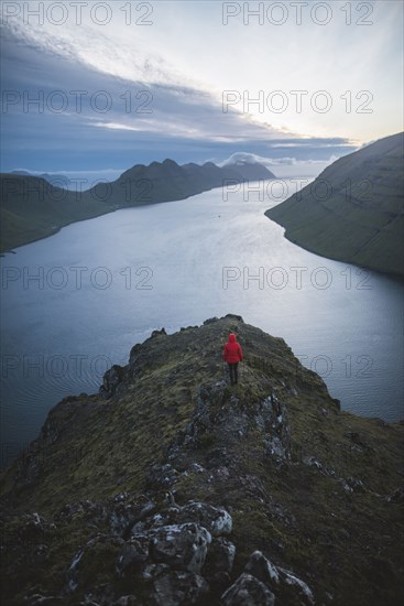 Woman standing on top of Klakkur mountain over sea and looking at view