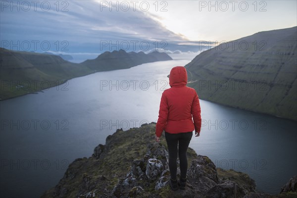 Woman standing on top of Klakkur mountain over sea and looking at view