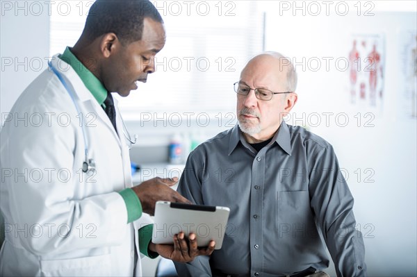 Doctor with digital tablet talking to patient