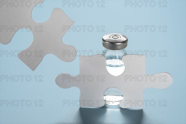 Vial of Covid-19 vaccine behind jigsaw puzzles