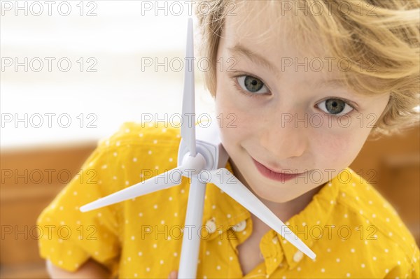 Portrait of boy (6-7) with wind turbine model