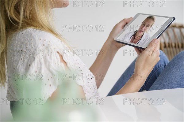 Woman having video call with female doctor via digital tablet