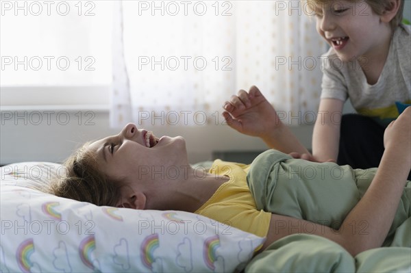 Brother (6-7) and sister (8-9) playing on bed