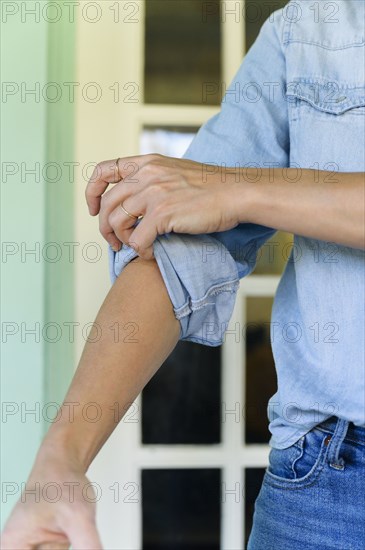 Close-up of woman rolling up sleeve
