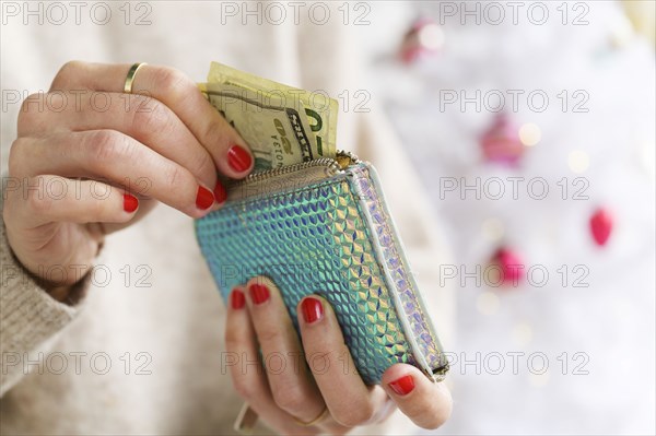 Hands holding wallet next to Christmas tree