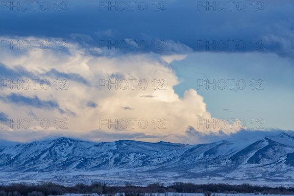 Snow dusted mountains and clouds over prairie