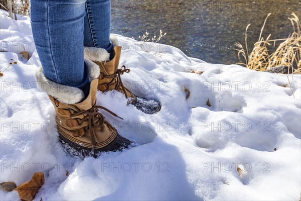 Legs of senior woman in hiking boots standing in snow