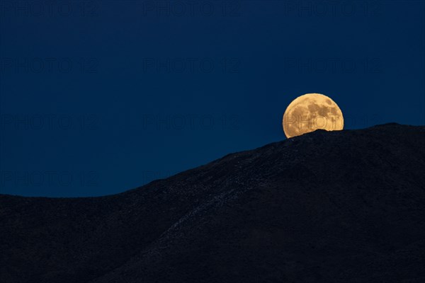 Full moon rising over hills