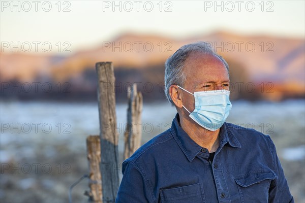Outdoor portrait of senior man wearing COVID protective mask