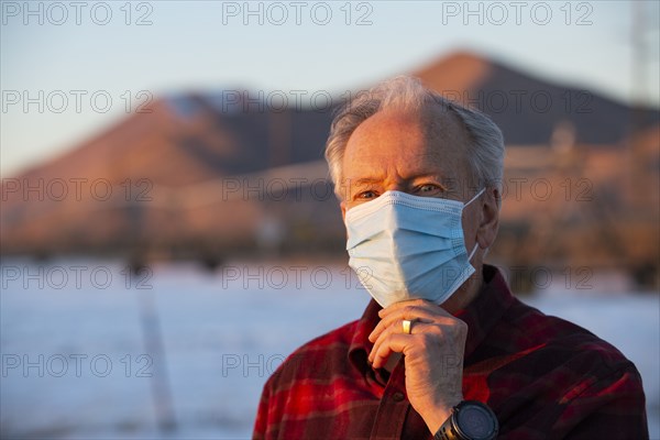 Outdoor portrait of senior man wearing COVID protective mask