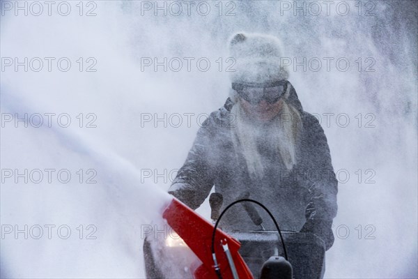 Senior woman clearing snow using snowblower