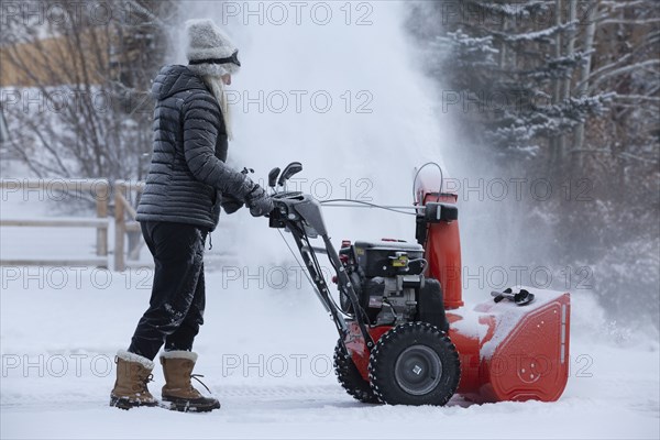 Senior woman clearing snow using snowblower