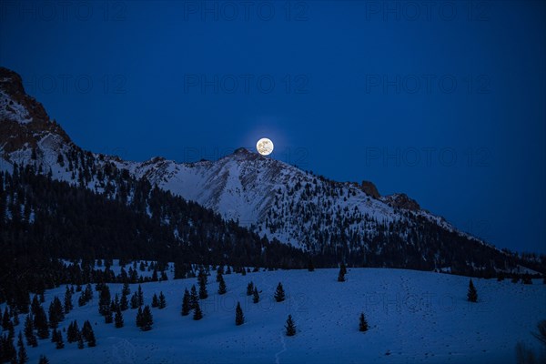 Full moon rising over Boulder Mountains in winter night