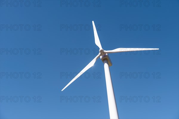 Low angle view of wind turbine against blue sky