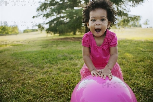 Black girl playing with ball in grass