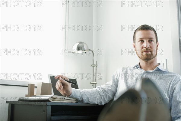 Caucasian businessman sitting at desk with feet up