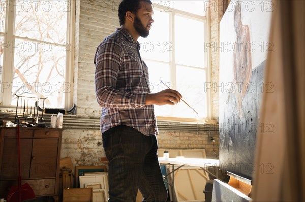 Mixed race artist painting in studio